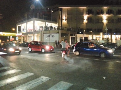 Piazza Tricolore a Catania. Sulla moto in due senza casco oltre la doppia striscia e bloccando le automobili